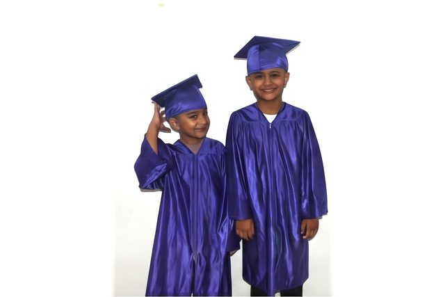 Two children smiling in graduation caps and gowns