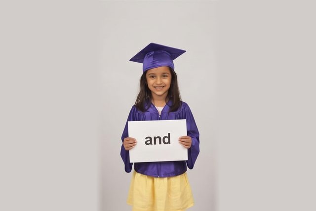 Graduate in cap and gown holding a word card: and