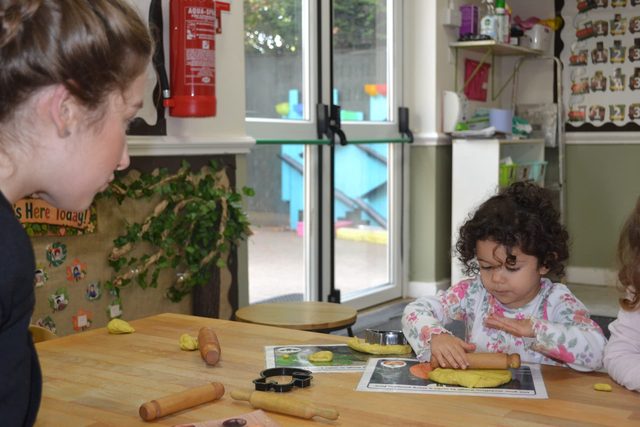 Child rolling playdough at the table