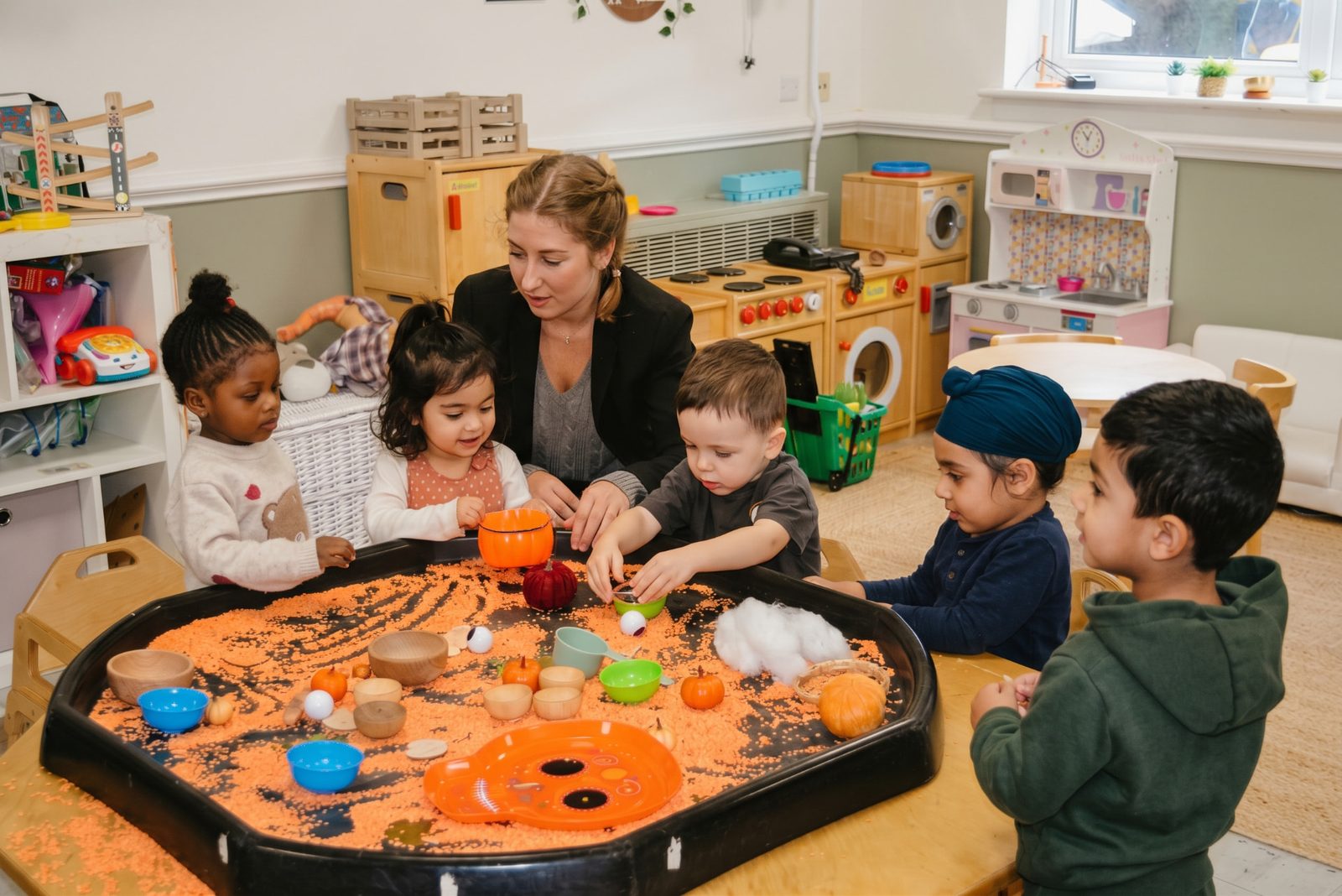 Practitioner and children exploring a sensory tray together