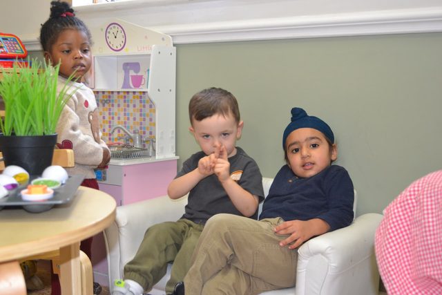 Children relaxing together on a sofa in the home corner