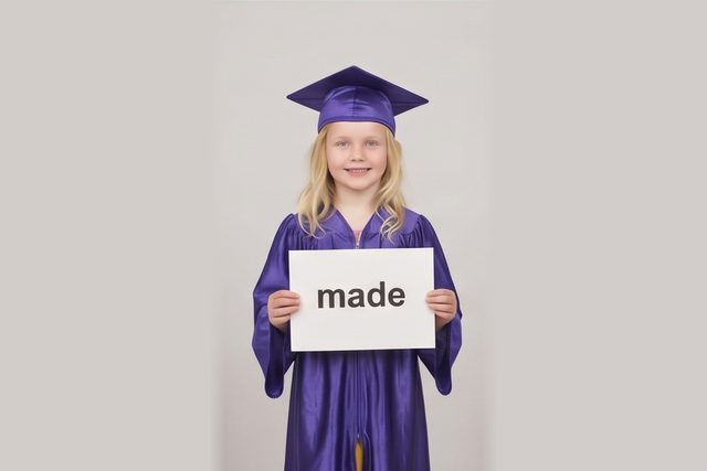 Graduate in cap and gown holding a word card: made