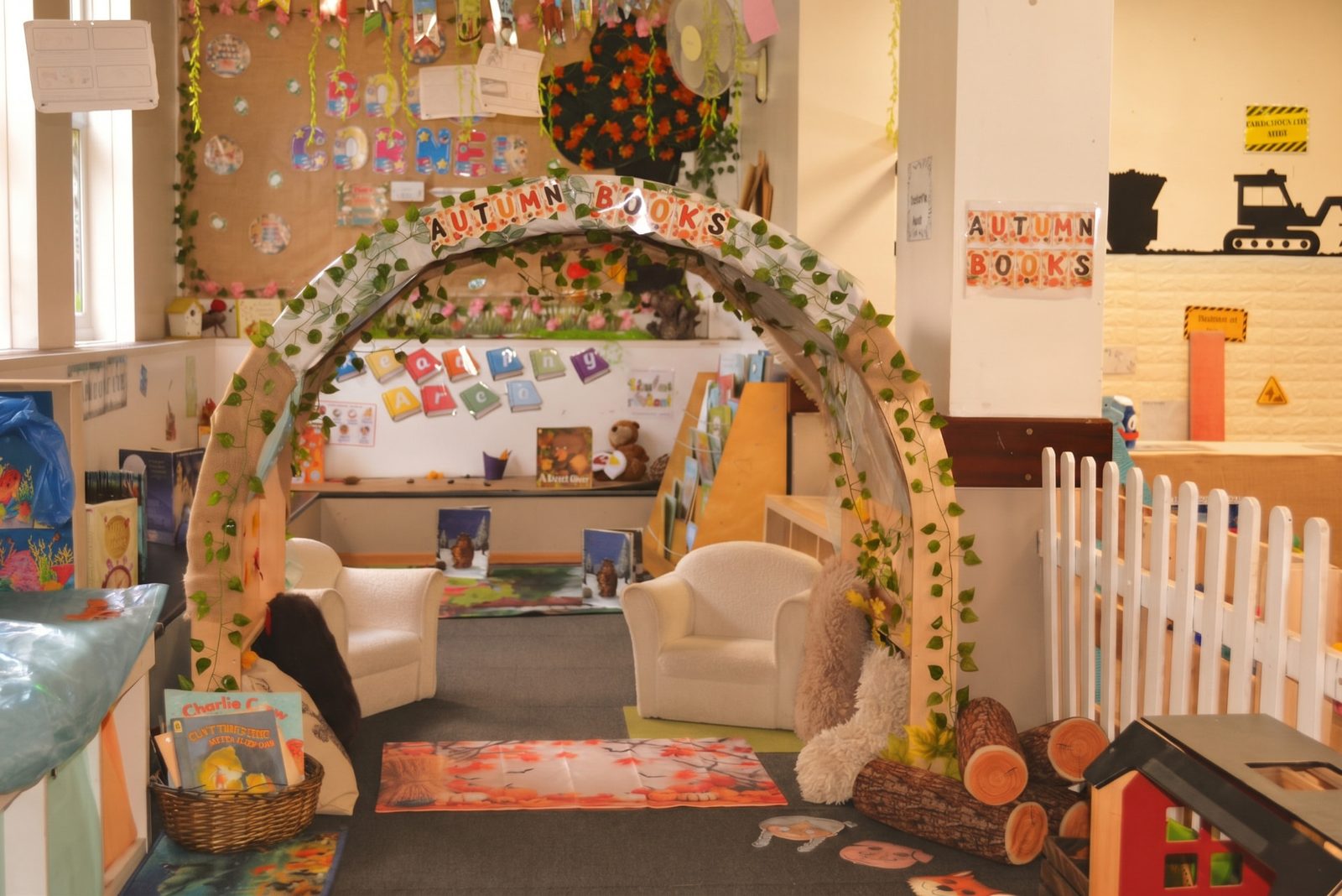 Pre-school reading area with a leafy autumn books arch and cosy armchairs