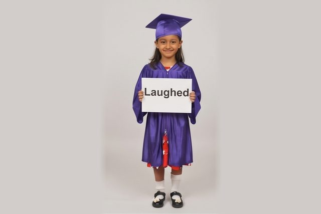 Graduate in cap and gown holding a word card: Laughed